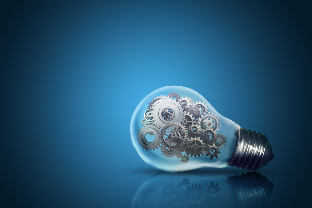 Close up of light bulb with gear mechanism inside isolated on dark blue background Close up of light bulb with gear mechanism inside isolated on dark blue background