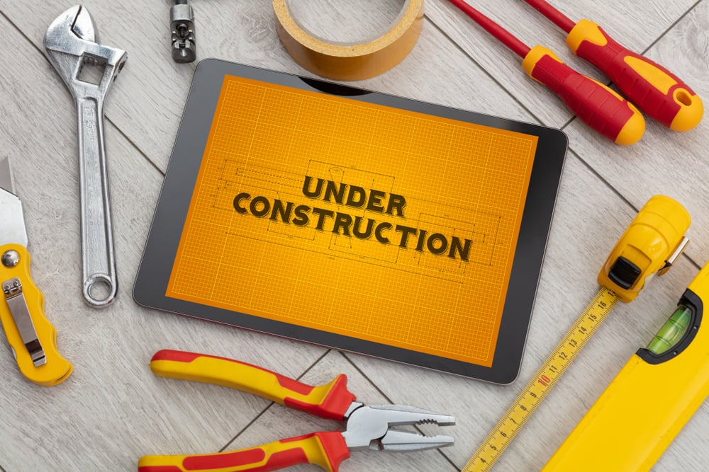 Tablet and tools with home under construction concept Tablet and tools with home under construction concept