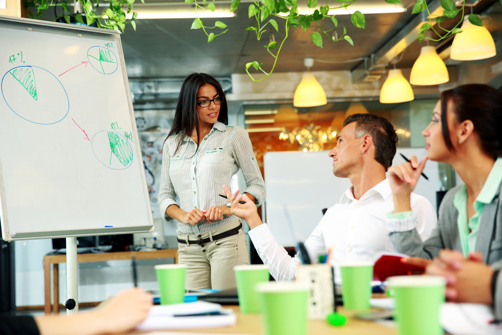 Young beautiful businesswoman explaining graph to his colleagues